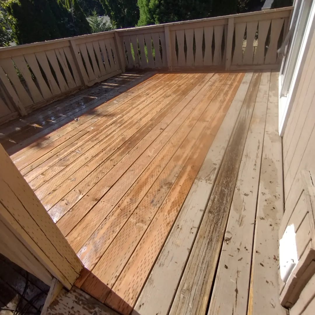 Wood deck halfway through a Curb Appeal power wash, washed boards bright next to grey unwashed boards