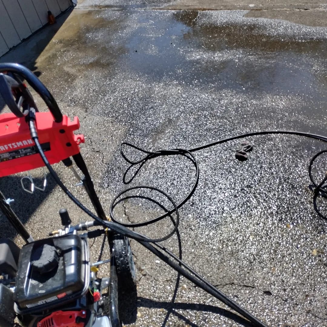The Curb Appeal pressure washer and hoses on a wet patio, set up for a job