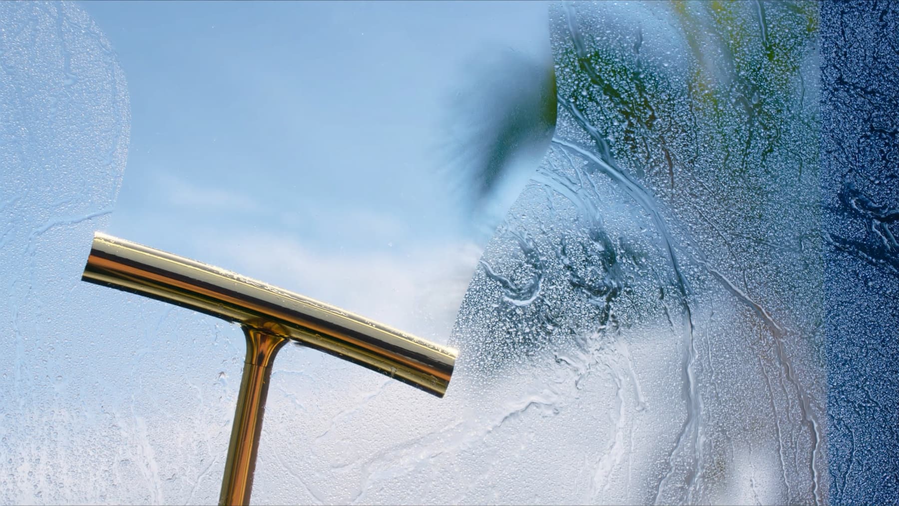 A squeegee pulling water off a pane of exterior glass, the finish Curb Appeal window cleaning leaves